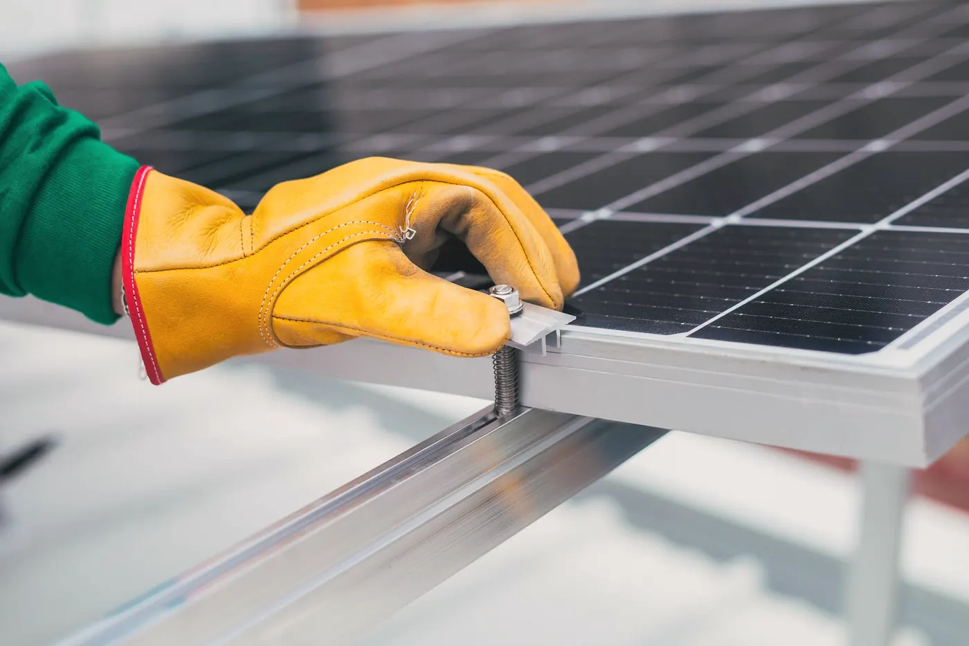 Gloved hand tightening a solar panel clamp