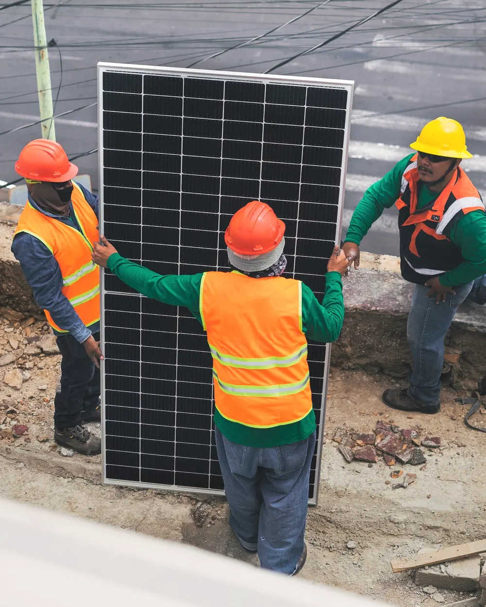 Three installers carrying a solar panel across a site